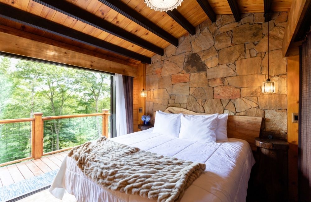 Meraki Escape in Brevard NC interior of bedroom with stone wall high ceilings private balcony