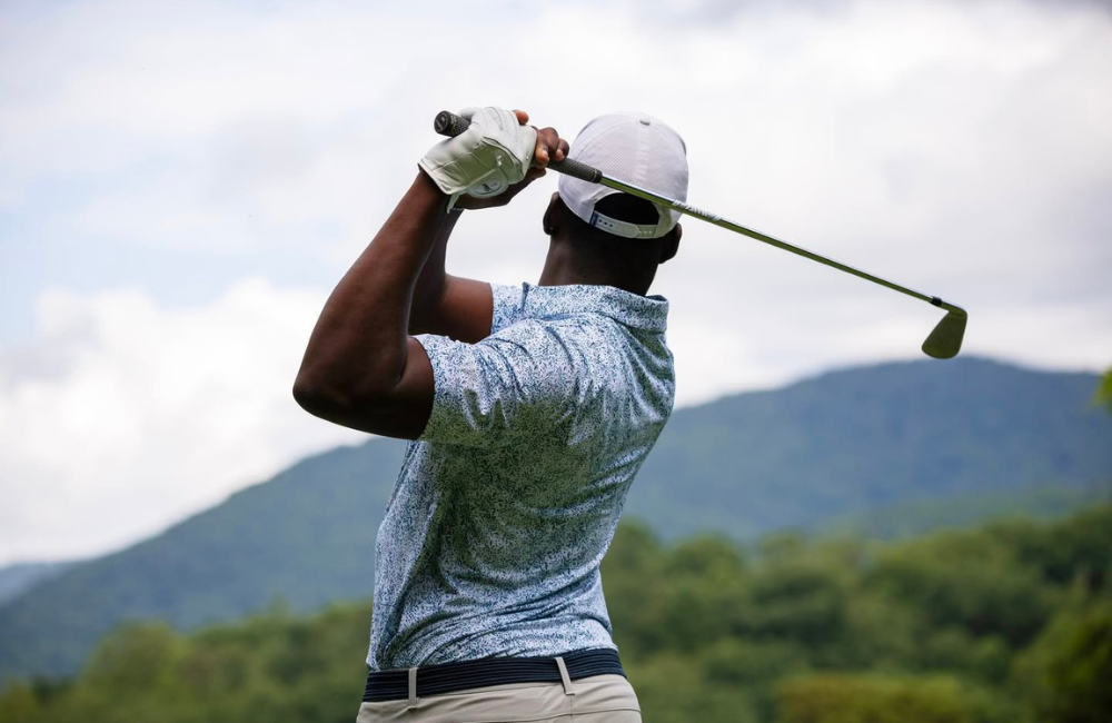 Man swinging golf club at a  scenic mountain golf course