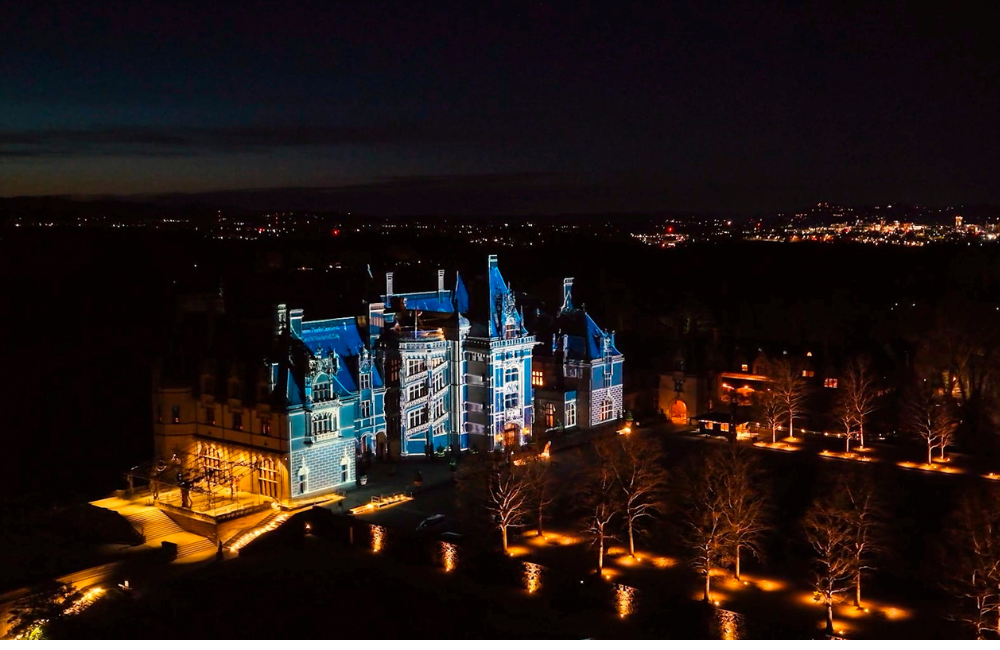 Aerial view of the Biltmore House lit for Luminere and with the color blue projected on the roof and exterior walls.