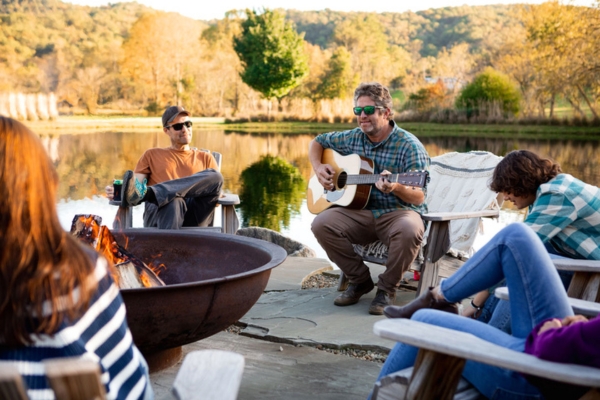 People circling around a campfire with a scenic backdrop in Brevard, NC. 