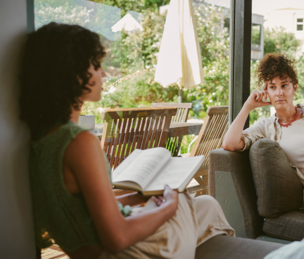 Two women sitting in a comfortable living room reading and talking