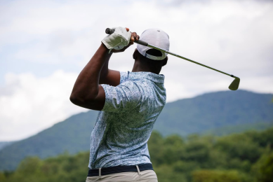 Man swinging a golf club at a mountain golf course